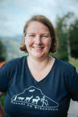 Yvonne Tremml, Hüttenwirtin auf dem Brünnsteinhaus Das Bild zeigt Yvonne Tremmel im blauen T-Shirt mit Werbung für das Brünnsteinhaus. Sie blickt lächelnd in die Kamera.