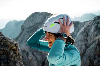 Frau im Gebirge setzt Helm auf