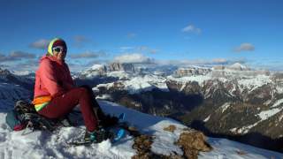 Frau mit Schneeschuhen macht Pause mit schöner Aussicht auf verschneite Gipfel