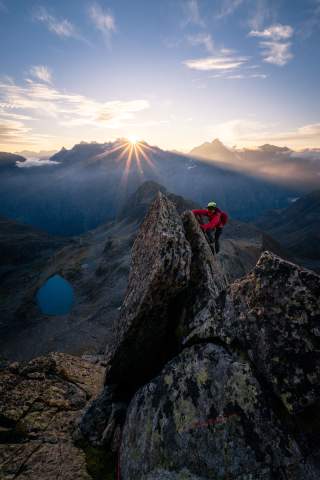 Mann klettert an Felsen bei Sonnenaufgang