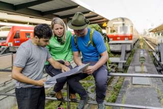 Drei Menschen studieren Karte an Bahngleis