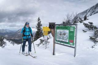 Skitourengeherin geht an Natürlich auf Tour-Schild vorbei