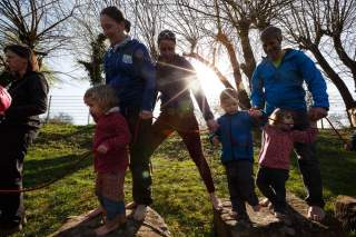 Erwachsene mit Kindern balancieren auf Steinen