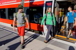 Drei Menschen steigen aus dem Zug aus