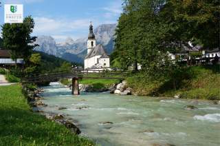 Bergbach mit Dorf und Kirche im Hintergrund