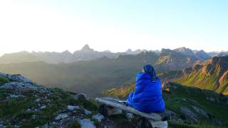 Frau beobachtet Sonnenaufgang unterm Nebelhorn im Allgäu