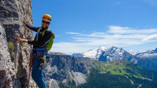 Mann klettert an Felswand bei strahlendem Sonnenschein