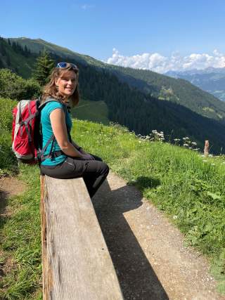 Frau sitzt auf Bank in den Bergen
