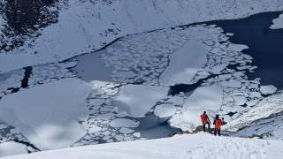 Zwei Personen vor einem See mit Eisschollen.