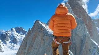 Person steht auf Gipfel und blick auf die Berge in der Umgebung.