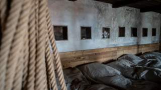 Im Vordergrund hängt ein Seil, dahinter das Matratzenlager in der Alten Prager Hütte mit Wandnischen für persönliche Gegenstände
