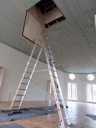 Große Leiter steht in Saal mit schön verzierter Decke