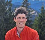 Mann in roter Jacke in den Bergen