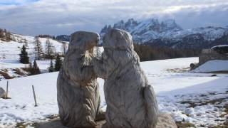 Zwei aus Holz geschnitzte Murmeltiere vor Bergkulisse