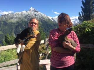 Zwei Frauen in den Bergen - eine mit einem Hund, eine mit einem Kaninchen auf dem Arm.