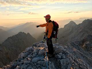 Mann auf Grat deutet ins Tal
