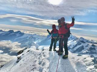 Drei Menschen auf schneebedecktem Gipfel