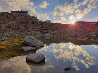 Sonnenuntergang an kleinem Bergsee mit Hütte im Hintergrund