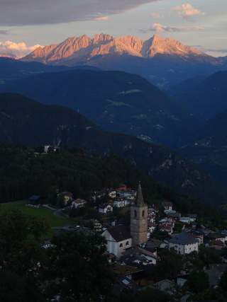 Bergdorf im Dunklen, Sonnenuntergang über den dahinterliegenden Bergen