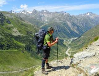Bepackter Wanderer steht auf Bergweg
