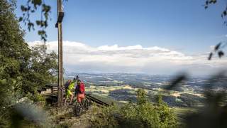 Zwei Menschen mit Mountainbikes schlagen auf Gipfel ein
