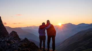 Zwei Personen Arm in Arm am Berg im Sonnenuntergang