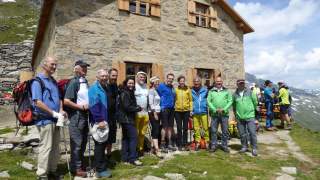 Eine Gruppe Menschen in Wandersachen steht vor der frisch restaurierten Alten Prager Hütte.