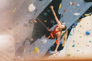 Hanna Meul, eine Athletin des DAV Nationalkaders, klettert an einer Indoorkletterwand. Sie ist angeseilt.