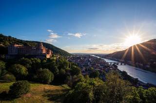 Areal view auf Heidelberg. Links das Schloss, auf der anderen Neckarseite geht hinter den Bergen die Sonne unter.