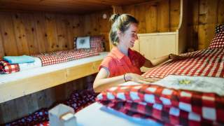 Junge Frau macht Stockbett in Hüttenzimmer