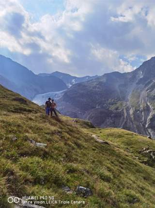 Paar steht in Bergwelt vor Gletscher