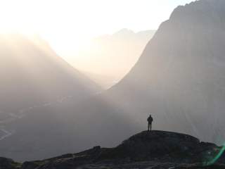 Mensch steht auf Bergkuppe vor weiter Landschaft