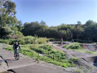 Ein asphaltierter Pumptrack mit mehreren Radfahrern