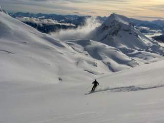 Mensch fährt in unberührter Winterlandschaft mit Ski von Berg runter