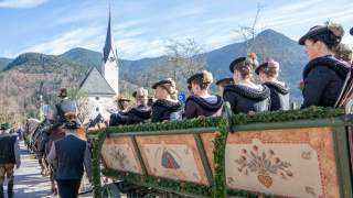 Kutsche mit Personen in Tracht fährt auf Kirche zu