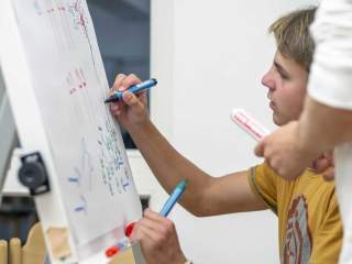 Ein Jugendliche*r zeichnet auf einem Flipchart