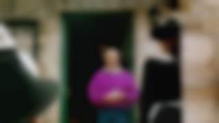 Josef Klenner auf dem Friesenberghaus in den Zillertaler Alpen. Er steht draußen vor der Eingangstür und hält eine Rede. Auf den Stufen sind drei Kinder zu sehen. Im Vordergrund Menschen, die Josef Klenner zugewandt sind.