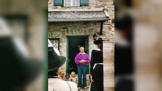 Josef Klenner auf dem Friesenberghaus in den Zillertaler Alpen. Er steht draußen vor der Eingangstür und hält eine Rede. Auf den Stufen sind drei Kinder zu sehen. Im Vordergrund Menschen, die Josef Klenner zugewandt sind.
