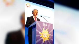 Josef Klenner am Rednerpult bei dem Festakt DAV 150 Jahre. Auf dem Rednerpult ist ein goldenes Edelweiß mit weißer Schrift "150 Jahre DAV, 1869-2019" abgebildet.