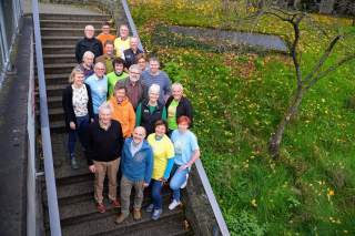 Mehrere Menschen stehen für ein Gruppenfoto auf einer Treppe.