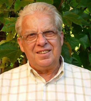 Mann mit Brille vor einer Hecke