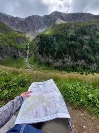 Mensch mit Karte blickt in Berglandschaft