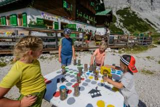 Kinder spielen Mensch ärgere dich nicht vor Berghütte