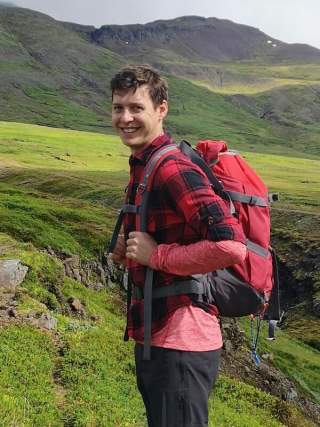 Junger Mann steht mit Wanderrucksack