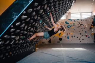Frau bouldert an Kilterboard in der Kletterhalle