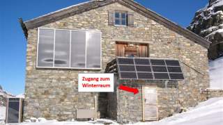 Steinhütte mit Solarpanels im Winter