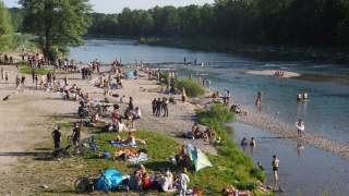 reges Treiben an der Isar. Badende und Spaziergänger*innen.