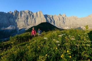 Zwei Menschen wandern vor Lalidererwänden mit Herzogkante