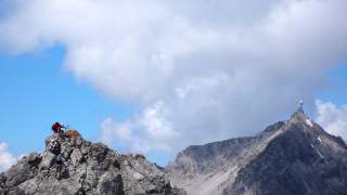 Drei Klettersteigbegeher auf dem Arlberger Klettersteig, dahinter die Valluga.