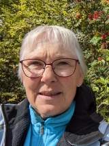 Frau mit Brille vor Hecke